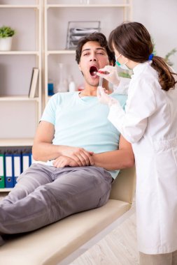 Genç ve yakışıklı bir adam, diş hekimini ziyaret ediyor.