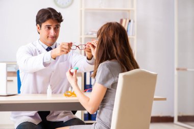 Genç bir kadın, erkek doktor göz doktorunu hastanede ziyaret ediyor.