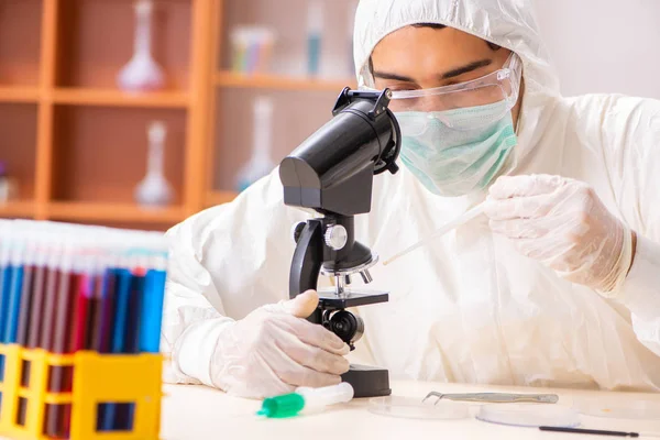 Joven bioquímico con traje protector trabajando en el laboratorio —  Fotos de Stock