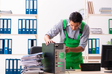 Ofiste bozuk bilgisayarı tamir eden genç bir mühendis. 