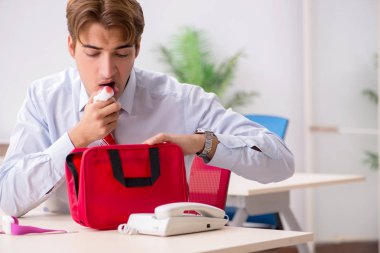 Ofiste ilk yardım çantası olan bir adam var.