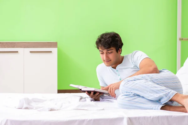 Giovane studente bello libro di lettura nel letto — Foto Stock