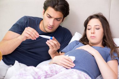 Genç koca hamile karısına bakıyor.