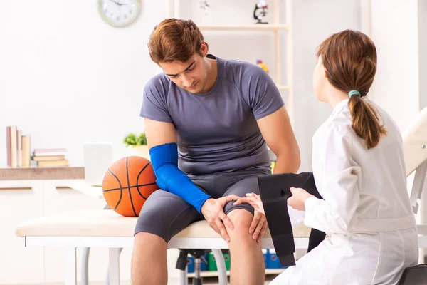 Guapo jugador de baloncesto visitando médico traumatólogo femenino — Foto de Stock