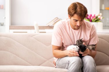 Genç adam evde kedi yavrusuyla oynuyor.