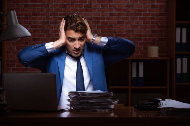 Genç işadamı geceleri ofiste çalışıyor. 