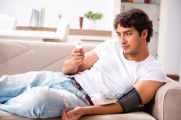 Hombre joven midiendo la presión arterial en casa — Foto de Stock