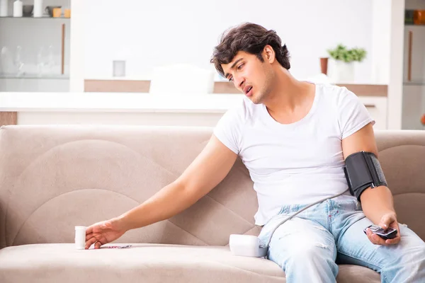 Hombre joven midiendo la presión arterial en casa — Foto de Stock