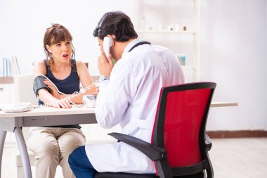 Genç doktor, kadınların tansiyonunu ölçüyor.