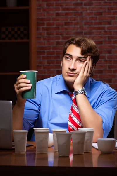 Empleado joven que bebe café trabajando en turno de noche — Foto de Stock