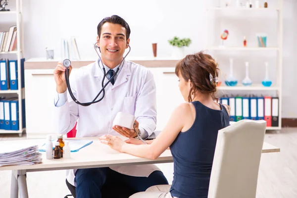 Young doctor checking womans blood pressure — Stock Photo, Image