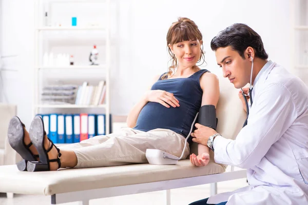 Ung läkare kontrollerar gravida kvinnor blodtryck — Stockfoto
