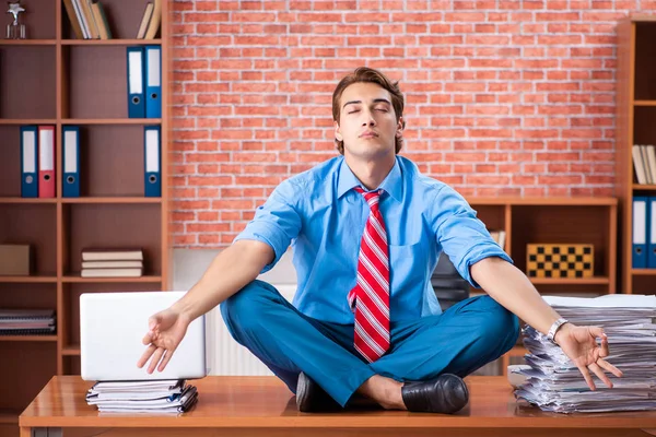 Jeune employé ayant un travail excessif assis au bureau — Photo