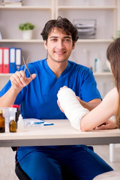 Jovem com braço enfaixado visitando médico traumotologis masculino — Fotografia de Stock