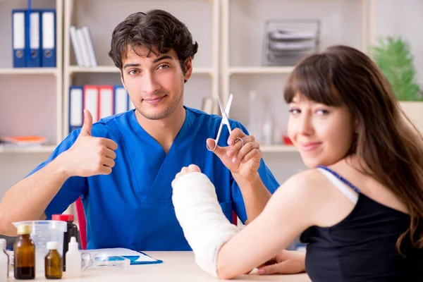 Молода жінка з перев'язаною рукою відвідує чоловічий лікар травматолог — стокове фото