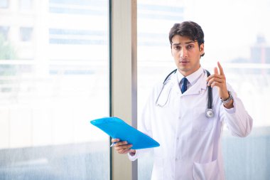 Genç yakışıklı doktor pencerede duruyor. 