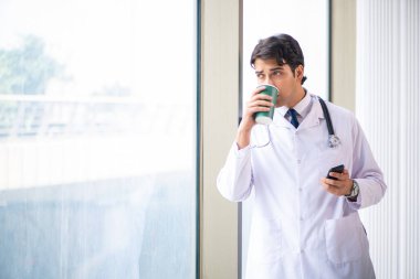 Genç yakışıklı doktor pencerede duruyor. 