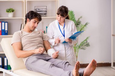 Kolu bandajlı genç adam kadın doktor travmatologunu ziyaret ediyor.