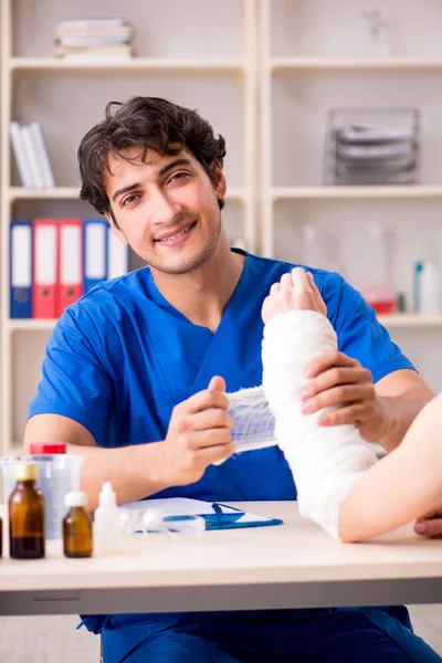 Young woman with bandaged arm visiting male doctor traumotologis — Stock Photo, Image