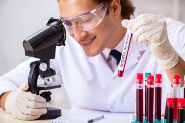 Genç yakışıklı laboratuvar asistanı hastanede kan örnekleri test ediyor. 