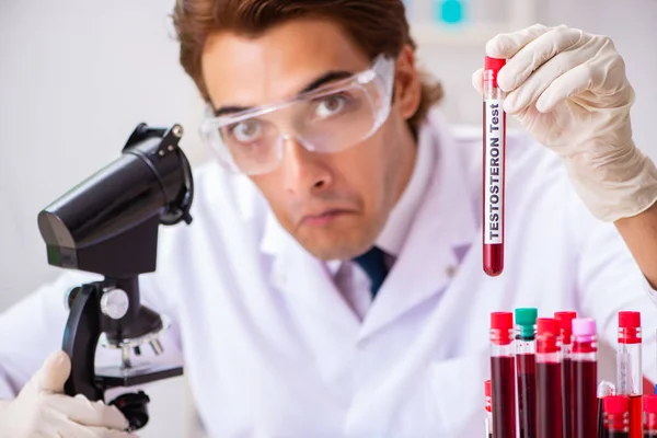 Asistente de laboratorio joven guapo analizando muestras de sangre en el hospital — Foto de Stock