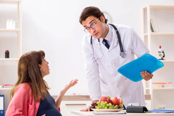 Mujer embarazada visitando al médico discutiendo dieta saludable —  Fotos de Stock