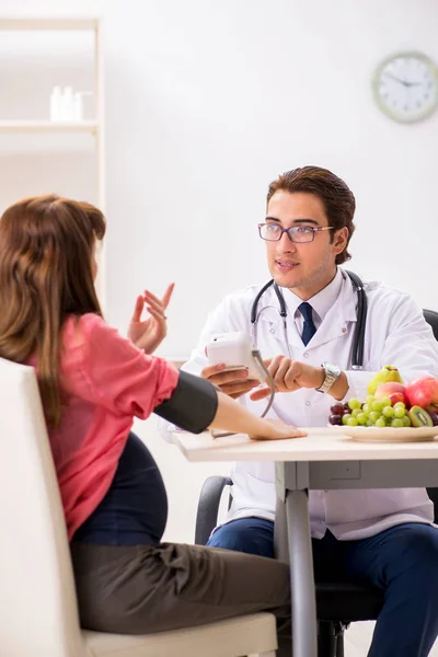 Pregnant woman visiting doctor discussing healthy diet