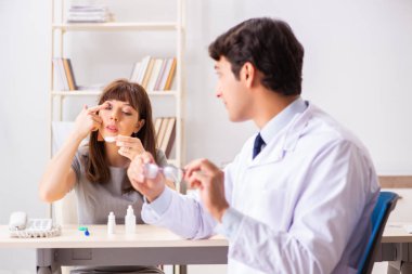 Genç bir kadın, erkek doktor göz doktorunu hastanede ziyaret ediyor.