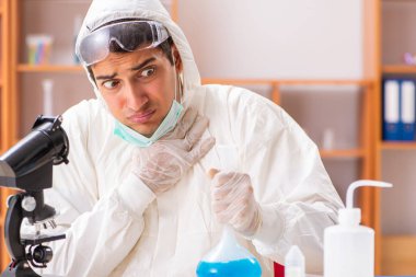 Laboratuvarda çalışan koruyucu elbise giyen genç bir biyokimyacı.