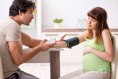 Koca hamile eşlerin tansiyonunu ölçüyor.