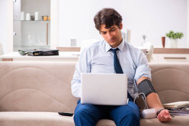 Stres altındaki adam kan basıncını ölçüyor.