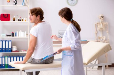 Erkek hasta genç bayan doktor kayropraktik uzmanını ziyaret ediyor. 