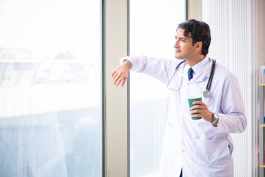 Genç yakışıklı doktor pencerede duruyor. 