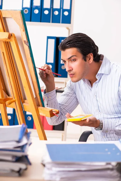Jovem e bonito funcionário desfrutando de pintura no escritório — Fotografia de Stock