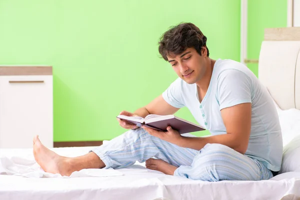 Jovem estudante bonito ler livro na cama — Fotografia de Stock