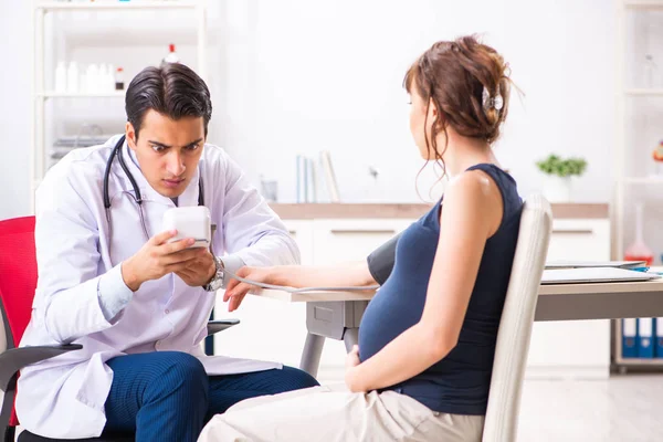 Ung läkare kontrollerar gravida kvinnor blodtryck — Stockfoto