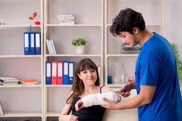 Young woman with bandaged arm visiting male doctor traumotologis — Stock Photo, Image