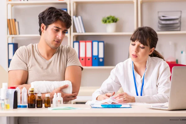 Young man with bandaged arm visiting female doctor traumatologis — Stock Photo, Image