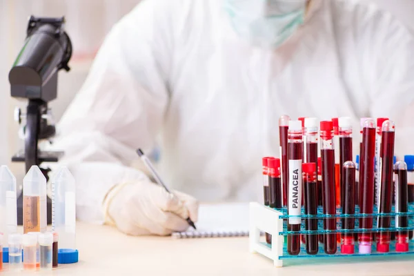 Asistente de laboratorio joven guapo analizando muestras de sangre en el hospital — Foto de Stock