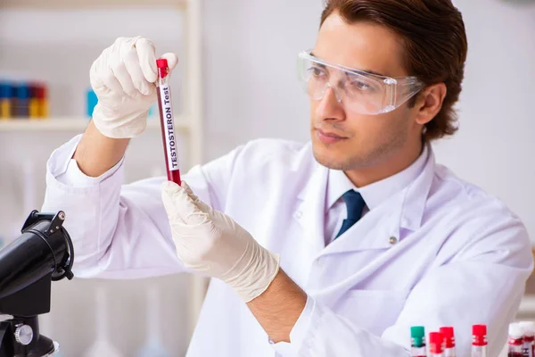 Asistente de laboratorio joven guapo analizando muestras de sangre en el hospital — Foto de Stock