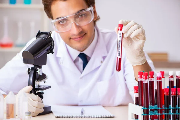 Asistente de laboratorio joven guapo analizando muestras de sangre en el hospital — Foto de Stock