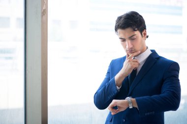 Genç yakışıklı işadamı pencerede duruyor. 