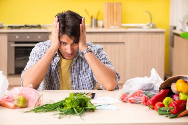Genç adam mutfakta sebze masraflarını hesaplıyor. 
