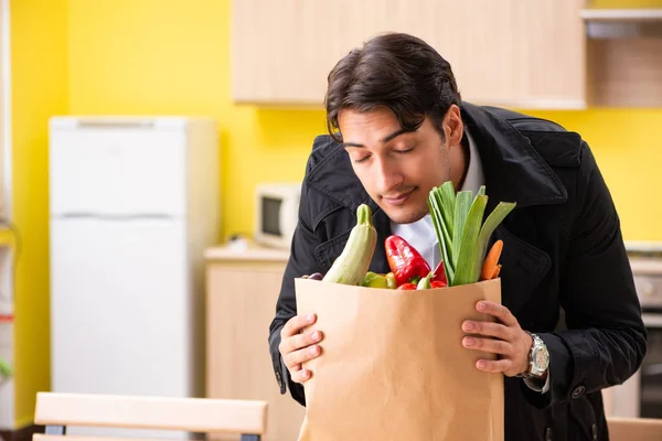 Ung stilig man med grönsaker i köket — Stockfoto