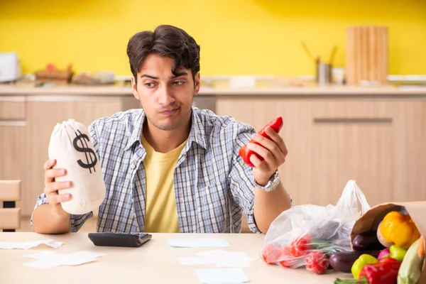 Young man calculating expences for vegetables in kitchen — Stock Photo, Image