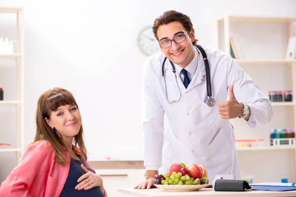 Mujer embarazada visitando al médico discutiendo dieta saludable —  Fotos de Stock