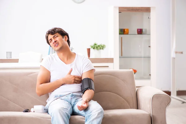 Hombre joven midiendo la presión arterial en casa — Foto de Stock