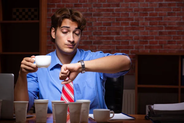 Empleado joven que bebe café trabajando en turno de noche — Foto de Stock