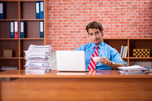 Ofiste aşırı işi olan genç bir çalışan oturuyor. — Stok fotoğraf