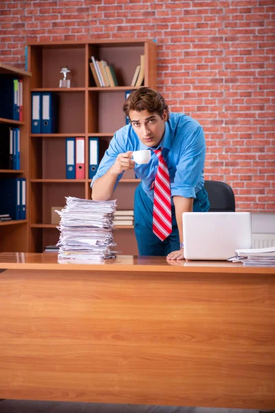 Jeune employé ayant un travail excessif assis au bureau — Photo